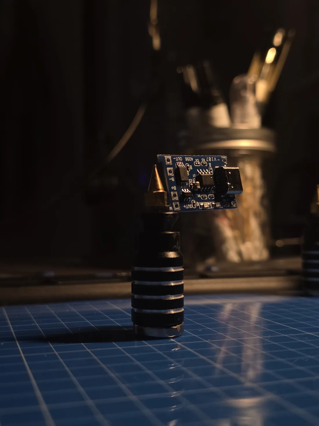 A small USB-C charging board held up on a soldering tip stand at the bench.